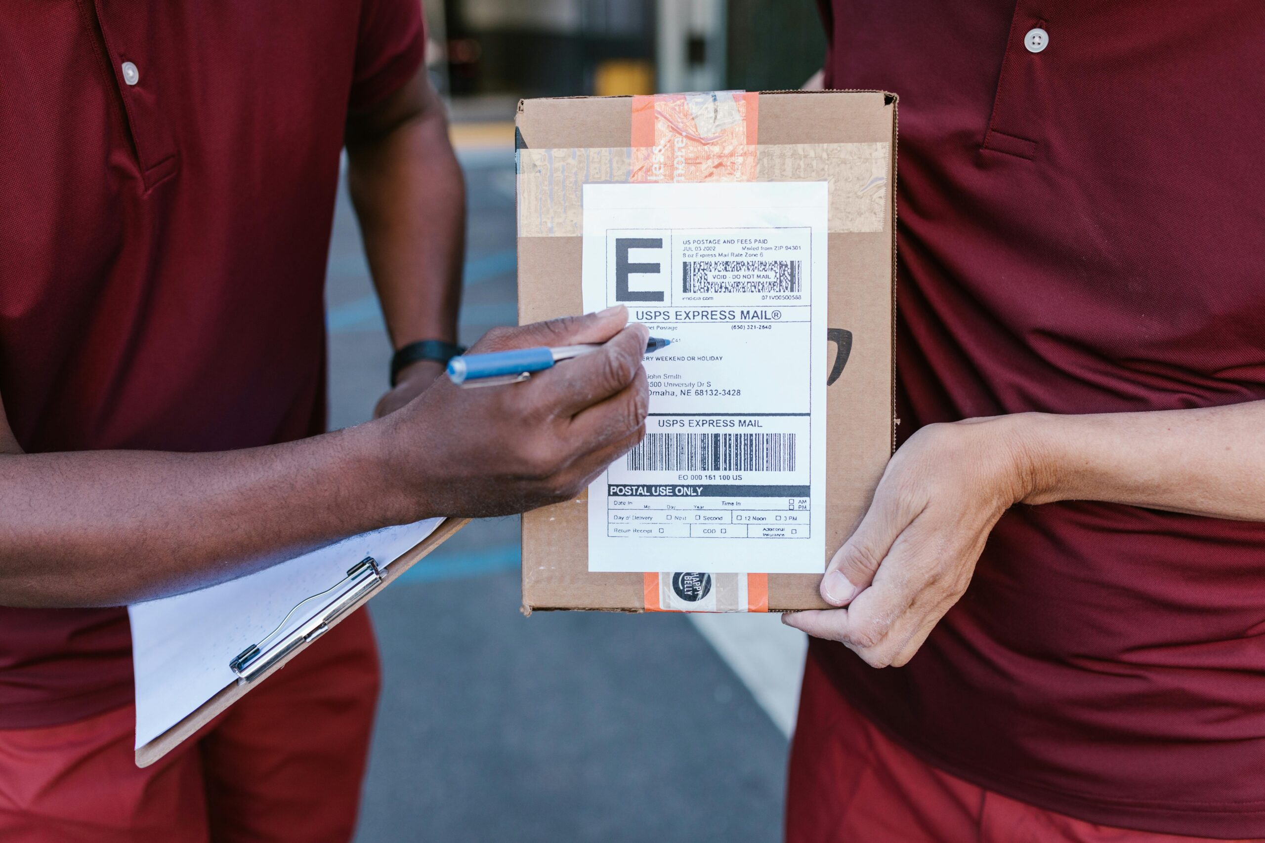 SHIPPING INFO Courier signing package delivery receipt on a clipboard outdoors.